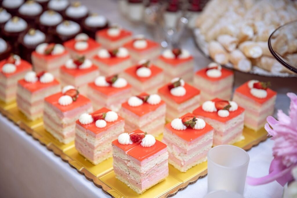 A tempting assortment of layered strawberry dessert slices with whipped cream on a dessert table.