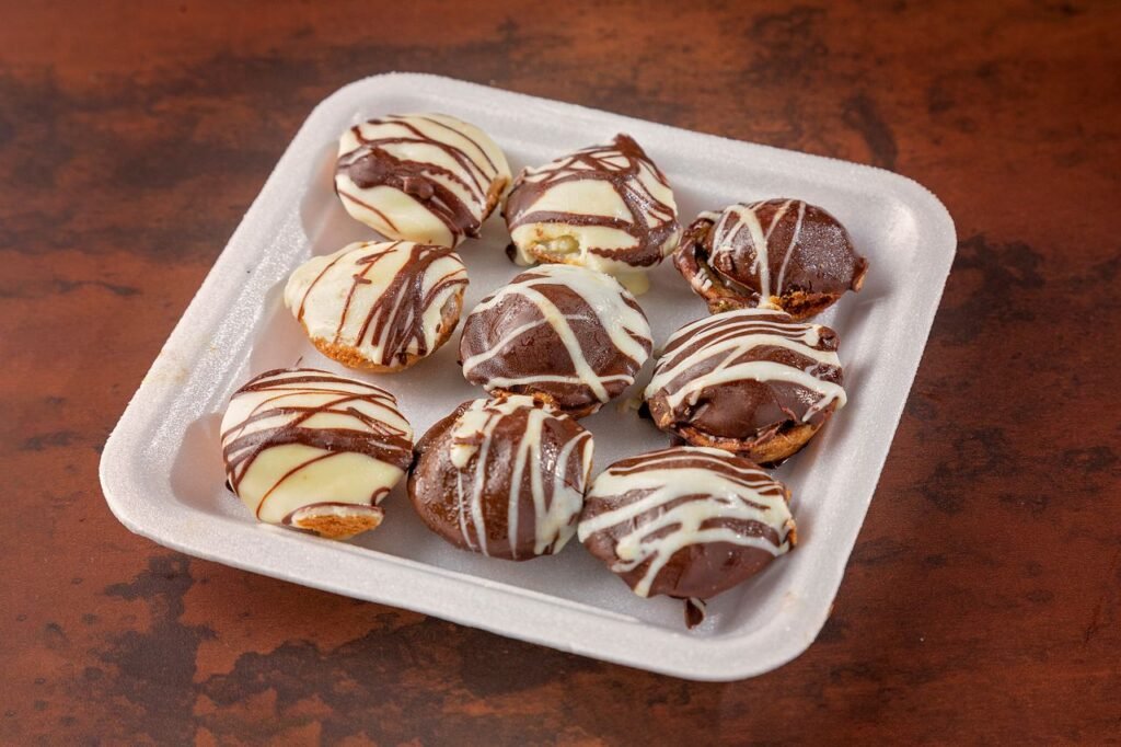 Menu Chocolate-covered pastries arranged on a tray with white and milk chocolate drizzles.