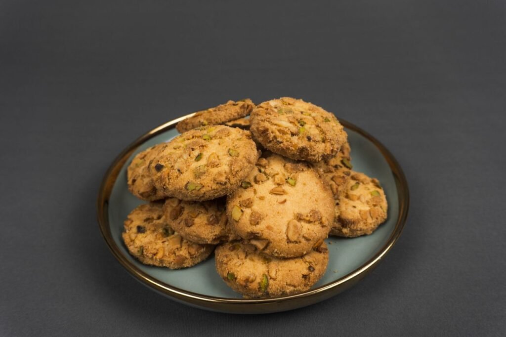 Menu A stack of delicious nutty cookies placed on a blue plate against a dark backdrop.