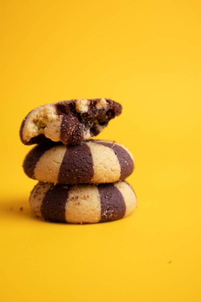 Menu Stack of chocolate vanilla swirl biscuits on a bright yellow background.