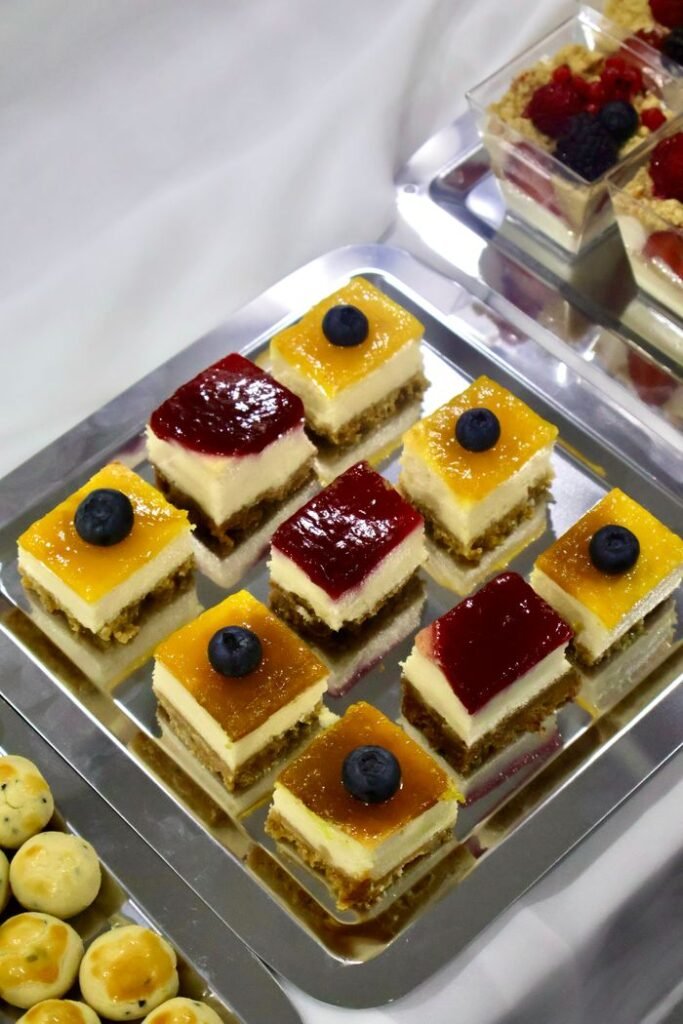 Menu Delicious cheesecake bites topped with blueberries and layered with fruit jelly on a serving tray.